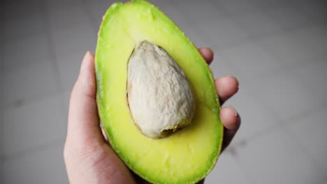 Hands-carefully-open-a-ripe-avocado,-revealing-its-creamy-green-flesh