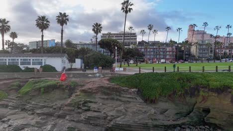 Drone-De-La-Jolla-Cove-Vuela-Horizontal-Hacia-Atrás-Lejos-Del-Parque-Y-Se-Aleja-Sobre-El-Océano