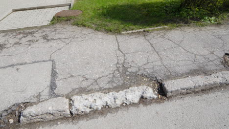 Sendero-De-Asfalto-Gris-Deteriorado,-Arcenes-Desaparecidos,-Baches-En-La-Carretera,-Mantenimiento-Público-Deficiente-Por-Parte-Del-Gobierno