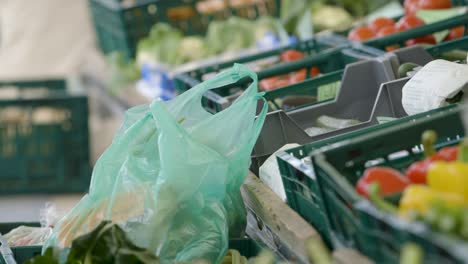 Close-up-view-of-green-plastic-bags-at-a-market-with-various-vegetables