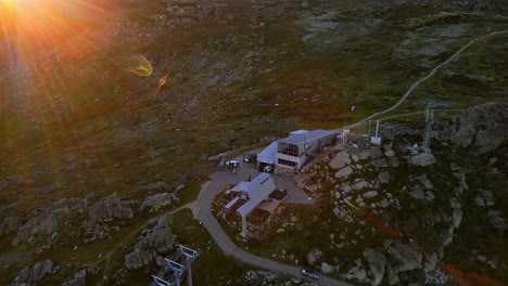 Aerial-of-Thredbo-ski-chairlift-and-mobile-network-towers-in-summer-dry-season-with-sun-lens-flare,-NSW,-Australia