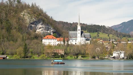 Traditionelles-Pletna-Boot-Mit-Touristen-Und-Wunderschöner-Kirche-Am-Bleder-See,-Slowenien