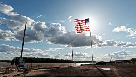 American-Flag-Waving-in-the-Wind-in-Front-of-the-Bright-Sun-in-Along-the-Mississippi-River-in-Grafton,-Illinois,-USA