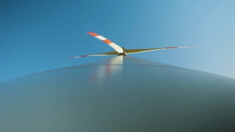 Dynamic-close-up-of-a-wind-turbine-blade-against-a-clear-blue-sky,-showcasing-sustainable-energy