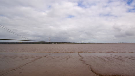 panning-wide-shot-of-the-Humber-bridge-showing-exposed-mud-flats-on-the-Humber-estuary-with-footpath