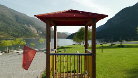Drone-passing-through-wooden-tower-for-lifeguard-along-shores-of-Molveno-lake,-Trentino-Alto-Adige-in-Italy