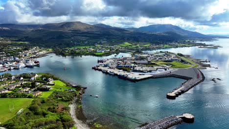 Drone-static-of-Castletownbere-fishing-port-with-fishing-trawlers-docked-in-the-sheltered-port-and-fishing-town-and-tourist-resort-area-in-background-with-the-mountains-surrounding-the-port