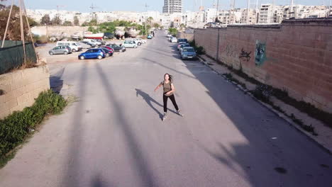 Slow-mo-active-track-drone-shot-of-a-young,-athletic,-caucasian-woman-inline-skating-on-the-streets-feeling-free-and-joyful