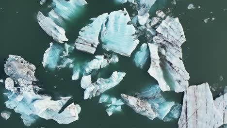 Aerial-shot-of-glaciers-floating-on-water-in-Iceland-during-winter-in-the-morning