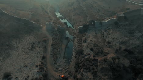 Hoher-Drohnenflug-über-Dem-Fluss-In-Der-Nähe-Historischer-Ruinen-Bei-Der-Ranikot-Festung-In-Sindh,-Pakistan