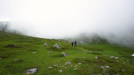 Two-people-hiking-alone-along-the-trail-in-the-clouds-on-mountains-on-a-sunny-day-in-Croatia