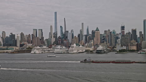 NYC-New-York-Aerial-v217-flyover-Hudson-river-capturing-towing-barge-on-the-waterway,-waterfront-piers-in-Hell's-Kitchen-and-cityscape-of-Midtown-Manhattan---Shot-with-Inspire-3-8k---September-2023