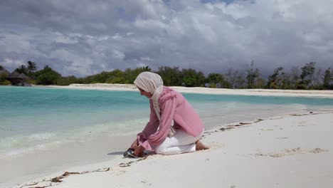 Woman-releases-a-young-sea-turtle-on-a-long-white-sandy-beach-in-the-Maldives