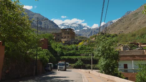 Weißer-Lastwagen-Fährt-Die-Straße-Im-Dorf-Imlil-Hinauf,-Im-Hintergrund-Der-Toubkal