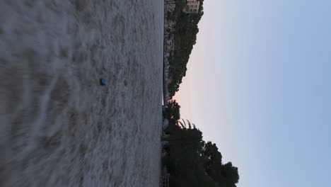 Vertical-aerial-view-of-idyllic-white-sand-beach-and-calm-lagoon-during-dusk