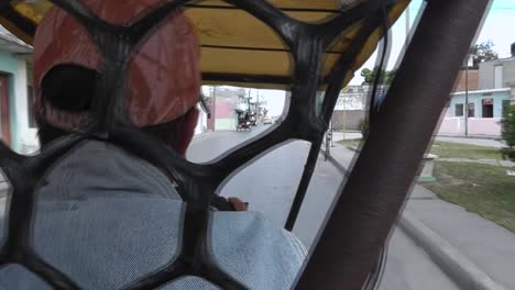 Sightseeing-view-from-the-backseat-of-a-traditional-Cuban-Cycle-Taxi-while-the-male-driver-is-pedaling-along-a-typical-city-street-in-order-to-transport-tourists-for-an-additional-small-income