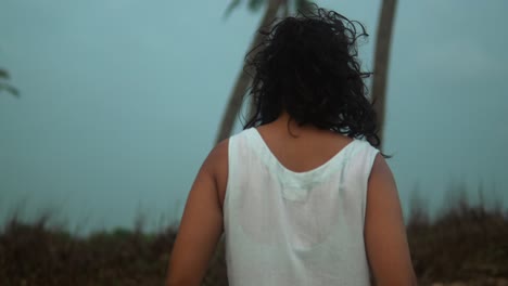 Mujer-Joven-Vestida-De-Blanco-Viendo-La-Puesta-De-Sol-Junto-Al-Océano,-Suave-Brisa-En-El-Cabello