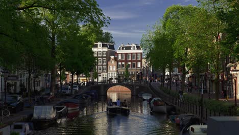 Escena-De-La-Vida-Cotidiana-En-Amsterdam-Con-Vistas-A-Un-Canal-Con-Un-Barco-Flotando