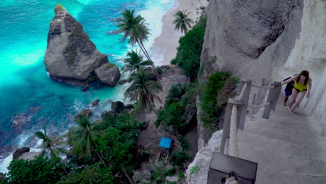 Unidentified-woman-and-man-climb-steep-stairs-at-Diamond-Beach-in-Nusa-Penida