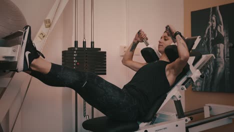 Young-woman-performs-leg-press-on-gym-machine,-slow-motion