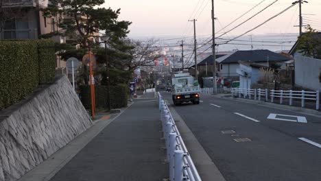 Carretera-De-Montaña-Con-Vistas-A-La-Ciudad,-Coches-Y-Camión-Grúa-Amarillo-Frente-A-La-Ciudad-De-Kobe-En-Japón