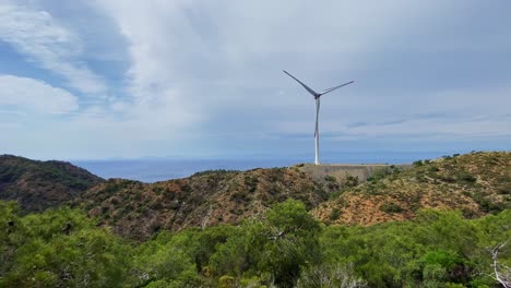 Sustainable-Resources-–-Single-wind-turbine-tower-among-wild-pine-tree-valley-landscape-of-Datça-peninsula-under-overcast-sky,-Aegean-Turkey