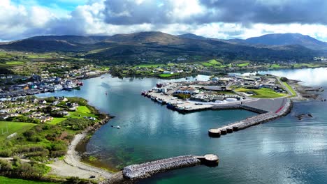 Drone-panning-shot-of-entrance-to-Castletownbere-fishing-port-and-town,-with-the-mountains-of-West-Cork-Ireland-on-the-Wild-Atlantic-Way-summer-morning