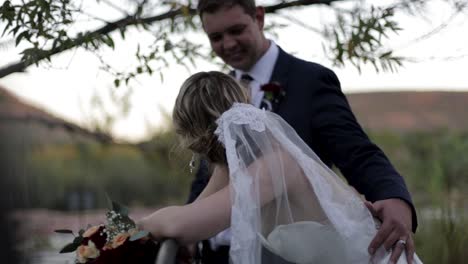 This-groom-is-standing-next-to-his-lovely-bride-and-leans-down-to-give-her-a-kiss-on-the-cheek