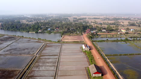 Vista-Panorámica-Aérea-De-Granjas,-Plantaciones-De-Sal-Y-Campos-De-Arroz-En-La-Camboya-Rural.