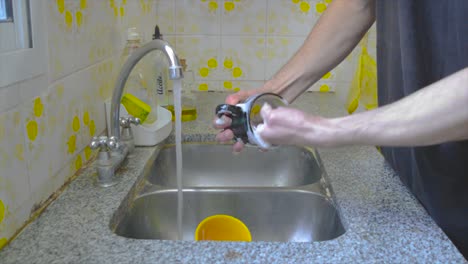 Male-person-washing-coffee-mug-at-home