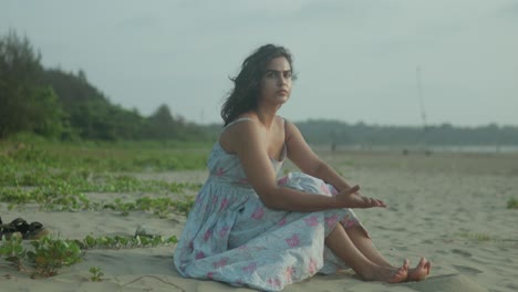 Mujer-Joven-Sentada-Pensativamente-En-Una-Playa-Tropical-Al-Atardecer,-Suaves-Olas-En-El-Fondo