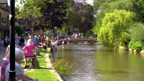 Toma-En-Cámara-Lenta-De-Bourton-on-the-water-En-El-Ajetreado-Y-Caluroso-Verano-Que-Muestra-El-Punto-De-Acceso-Turístico-De-Los-Cotswolds