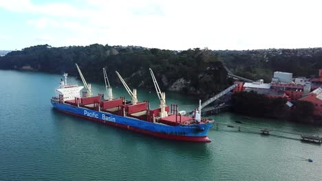 Aerial-Pan-of-cargo-ship-crane-offloading-sugar-in-Chelsea-Sugar-Factory,-Auckland-harbor,-New-Zealand-4k