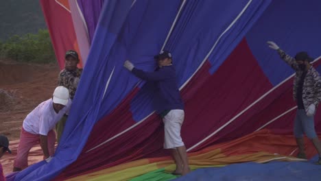 Ein-Heißluftballon-Ist-Gerade-Gelandet-Und-Männer-Aus-Laos-Helfen-Sich-Gegenseitig,-Ihn-Zusammenzupacken