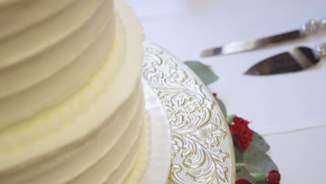Close-up-of-vanilla-wedding-cake-with-knives-in-the-background
