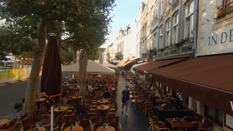 Slow-motion-dolly-shot-high-over-crowded-cafe-terraces-on-a-sunny-day-at-the-famous-Vrijthof,-the-main-square-of-Maastricht,-the-Netherlands