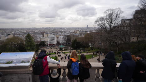 Fotografía-Cenital-En-Movimiento-De-Turistas-Contemplando-La-Ciudad-De-París-Desde-La-Terraza-De-La-Basílica-Del-Sacre-Coeur-Durante-Un-Día-Nublado-De-Invierno.