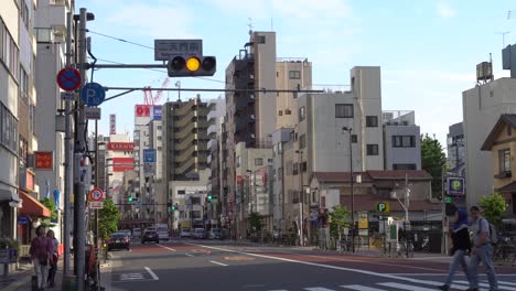 Tráfico-De-Automóviles-En-Tokio-Asakusa-Con-Peatones-Cruzando-La-Calle-Umamichi-Dori-En-Un-Cruce-De-Cebra