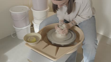 a-woman-centering-clay-on-the-pottery-wheel