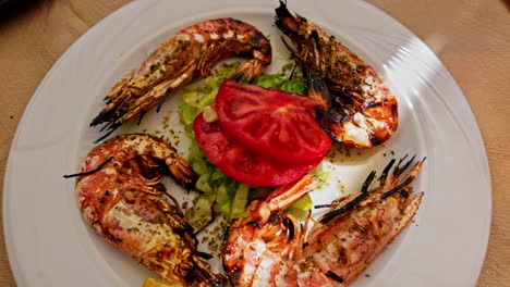 Fresh-grilled-tiger-shrimps-with-tomato-and-lettuce-served-in-restaurant,-close-up