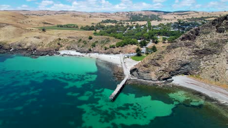 A-4k-drone-shot-flying-backwards-to-reveal-a-long-jetty-sticking-out-into-a-bright-blue-ocean