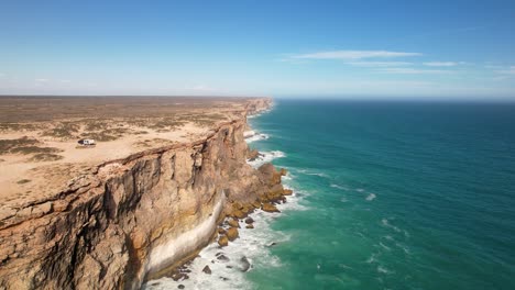 Drone-view-of-impressive-tall-cliffs-and-the-waves-crashing-against-them-below