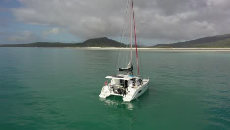 Tourists-raise-sail-on-rented-catamaran-sailboat-off-Whitsunday-Island