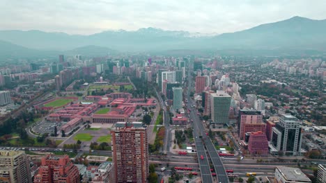 Drone-Aéreo-Vuela-Brumoso-Barrio-De-Santiago-De-Chile-Cordillera-Fondo-Montañoso,-área-Verde-Urbana-Alrededor-De-La-Escuela-Militar