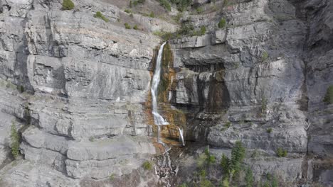 Aerial-push-in-and-pan-up-of-mountains-beyond-Bridal-Veil-Falls-in-American-Fork-Canyon,-Utah-during-spring