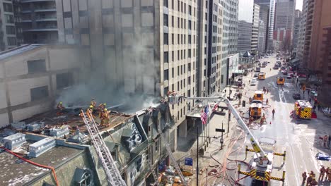 Firefighters-and-fire-trucks-extinguishing-major-fire-in-city-building,-dangerous-intervention,-aerial