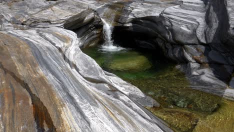 Wunderschöner-Bach-Mit-Wasserkaskaden,-Die-Einen-Flachen-Pool-Mit-Gewaschenen-Steinen-Formen