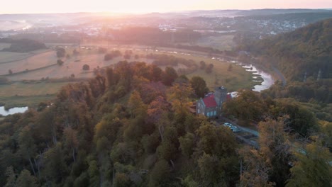 Vibrant-sunrise-over-Ruhr-river-and-Isenburg-castle,-aerial-drone-pullback