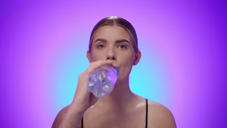 Caucasian-woman-enjoys-fresh-water-from-plastic-bottle,-studio-shot