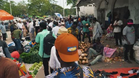 Lady-in-white-shirt-wearing-hat-walking-through-crowd-on-busy-noisy-african-market-place